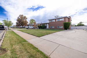 Exterior space featuring fence, a front lawn, and brick siding