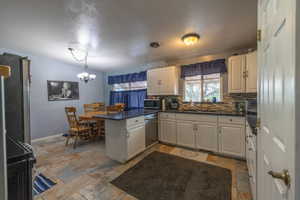 Kitchen with decorative backsplash, appliances with stainless steel finishes, a sink, a peninsula, and stone tile flooring