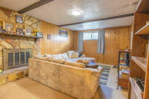 Living area featuring carpet floors, a textured ceiling, beamed ceiling, and wood walls