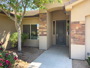 View of exterior entry with stucco siding and stone siding