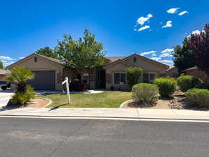 Single story home with a garage, stucco siding, a front lawn, concrete driveway, and a tiled roof