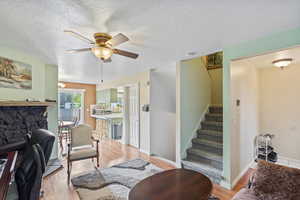 Living room featuring stairs, a textured ceiling, and light wood-style floors