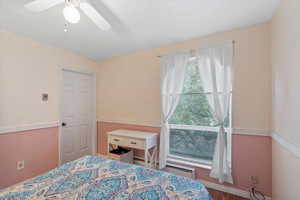 Bedroom with a ceiling fan, baseboards, baseboard heating, and wood finished floors