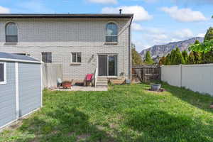 Back of property with entry steps, a mountain view, a lawn, and a fire pit