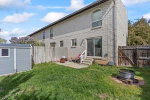 Rear view of house featuring a fenced backyard, an outbuilding, a yard, and entry steps