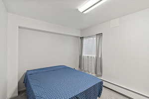 Carpeted bedroom with baseboards and a baseboard radiator
