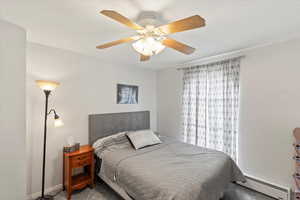 Bedroom with carpet floors, a ceiling fan, baseboards, and a baseboard heating unit