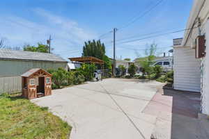 View of patio featuring fence, area for grilling, a pergola, and an outbuilding
