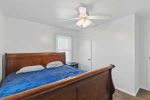 Carpeted bedroom with a ceiling fan and baseboards