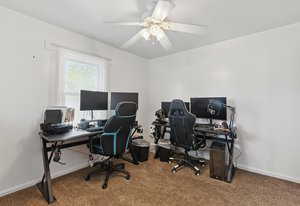 Carpeted office with baseboards and a ceiling fan