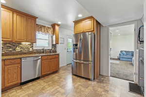 Kitchen with backsplash, recessed lighting, appliances with stainless steel finishes, and baseboards