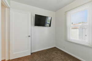 Empty room featuring dark carpet and baseboards