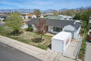 View of front facade with a garage, a mountain view, a shingled roof, and a residential view