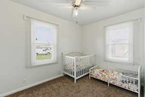 Bedroom featuring baseboards, a nursery area, a ceiling fan, and carpet