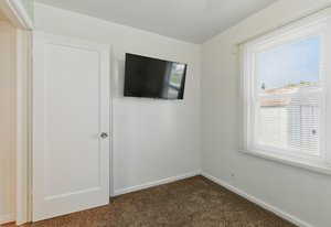 Spare room with dark colored carpet and baseboards