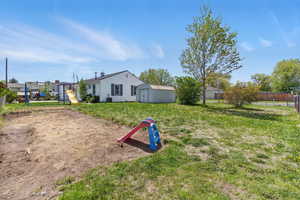 View of yard featuring fence, an outbuilding, a shed, and a playground
