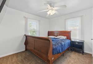 Carpeted bedroom featuring baseboards and a ceiling fan