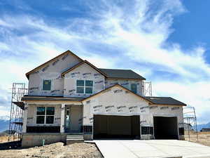 Property under construction featuring a garage, concrete driveway, and a porch