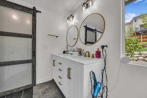 Master bathroom featuring baseboards, double vanity, barn door
