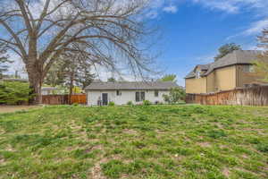 Rear view of property featuring a lawn and fence
