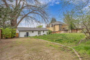 Back of property with a fenced backyard, a shingled roof, and a lawn