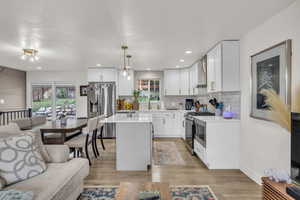 Kitchen featuring backsplash, appliances with stainless steel finishes, wall chimney range hood, and light countertops