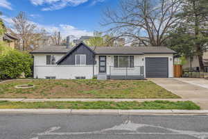 View of front of home with concrete driveway, board and batten siding, a chimney, a shingled roof, and a garage