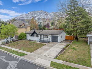 Single story home featuring a garage, a mountain view, a front lawn, and driveway