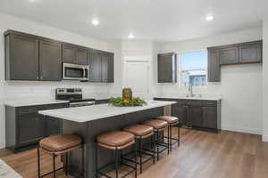 Kitchen with light wood-style flooring, a kitchen island, appliances with stainless steel finishes, and a breakfast bar area