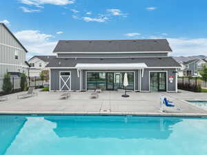 Rear view of house with a community pool, a shingled roof, a patio, and fence