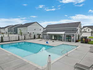Community pool with fence, a patio area, and a residential view