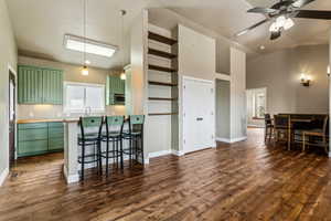 Kitchen with baseboards, dark wood-style floors, stainless steel microwave, a ceiling fan, and green cabinets
