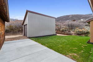 View of yard with an outdoor structure, fence, a mountain view, and a garage