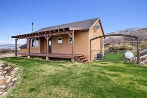 Rear view of property with fence, cooling unit, stucco siding, a shingled roof, and a lawn