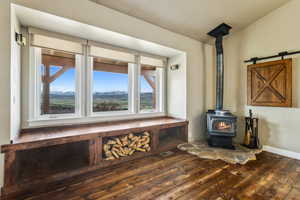 Room details with baseboards, a wood stove, and wood finished floors