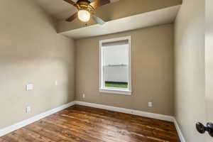 Spare room featuring baseboards, visible vents, dark wood-style floors, and ceiling fan