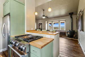 Kitchen featuring dark wood-style flooring, stainless steel appliances, wood counters, and green cabinets