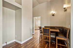 Dining area with baseboards, high vaulted ceiling, and wood finished floors