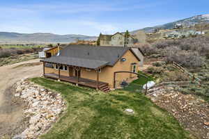Rear view of house featuring fence, a mountain view, a yard, a shingled roof, and stucco siding