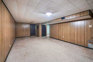 Family room featuring tile patterned floors, wood walls, and visible vents