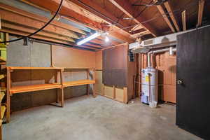 Unfinished below grade area with strapped water heater, a workshop area, and visible vents
