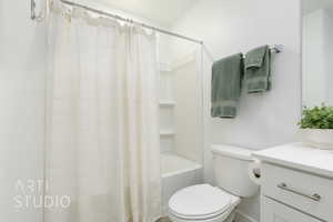 Full bathroom with shower / tub combo with curtain, toilet, and vanity