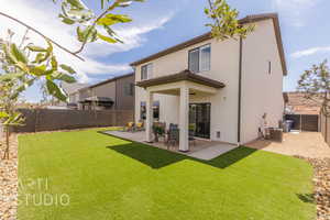 Back of property with stucco siding, a patio area, a yard, and a fenced backyard