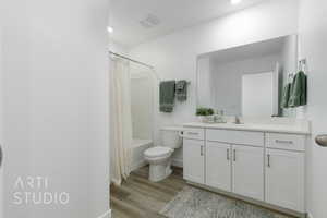 Bathroom with shower / bathtub combination with curtain, vanity, toilet, visible vents, and wood finished floors