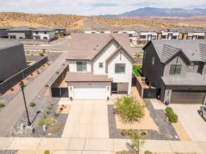 View of front of home featuring a residential view, concrete driveway, an attached garage, and stucco siding