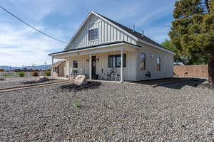 Modern farmhouse style home featuring a porch, board and batten siding, fence, and a mountain view