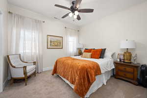 Bedroom featuring visible vents, baseboards, ceiling fan, and light carpet
