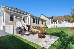 Rear view of property with stucco siding, a fenced backyard, a patio, a yard, and a fire pit