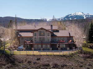 Rear view of house with a fenced backyard, a mountain view, a chimney, and a patio