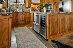 Kitchen featuring backsplash, stainless steel appliances, brown cabinetry, and beverage cooler